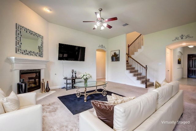 1328 Sandpiper Dr, Forney, TX 75126 - carpeted living area with arched walkways, stairway, a ceiling fan, a glass covered fireplace, and baseboards