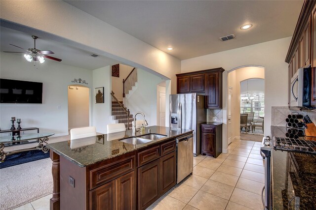1328 Sandpiper Dr, Forney, TX 75126 - kitchen with a sink, stainless steel appliances, arched walkways, a ceiling fan, and dark stone counters