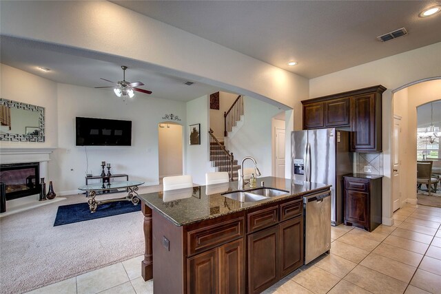 1328 Sandpiper Dr, Forney, TX 75126 - kitchen with stainless steel appliances, arched walkways, a sink, dark stone countertops, and light tile patterned floors