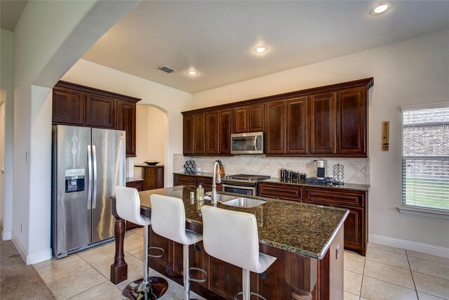 1328 Sandpiper Dr, Forney, TX 75126 - kitchen with appliances with stainless steel finishes, arched walkways, dark stone counters, backsplash, and recessed lighting