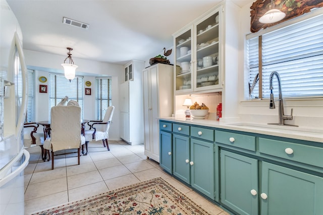 1467 Limerick Ct, Keller, TX 76262 - kitchen with freestanding refrigerator, light countertops, light tile patterned flooring, decorative light fixtures, and glass insert cabinets