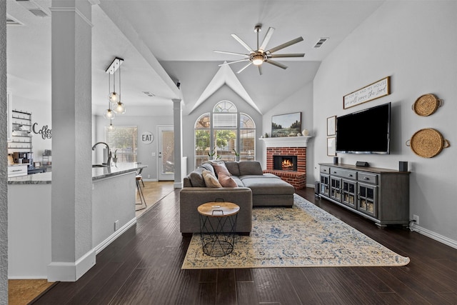 712 Saint Robby Dr, Mansfield, TX 76063 - living area featuring ornate columns, ceiling fan, a brick fireplace, baseboards, and dark wood finished floors