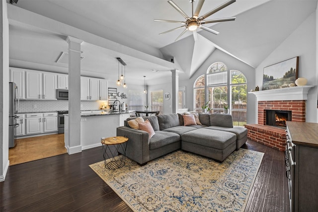 712 Saint Robby Dr, Mansfield, TX 76063 - living area featuring decorative columns, a ceiling fan, a brick fireplace, dark wood-type flooring, and lofted ceiling