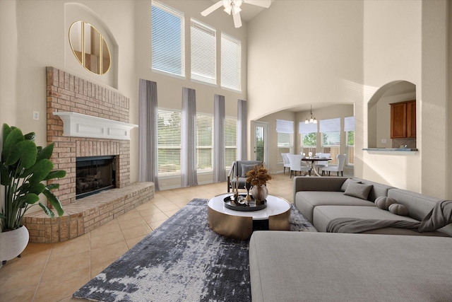 700 Sage Brush Dr, Weatherford, TX 76087 - living room featuring light tile patterned floors, a high ceiling, ceiling fan, arched walkways, and a fireplace