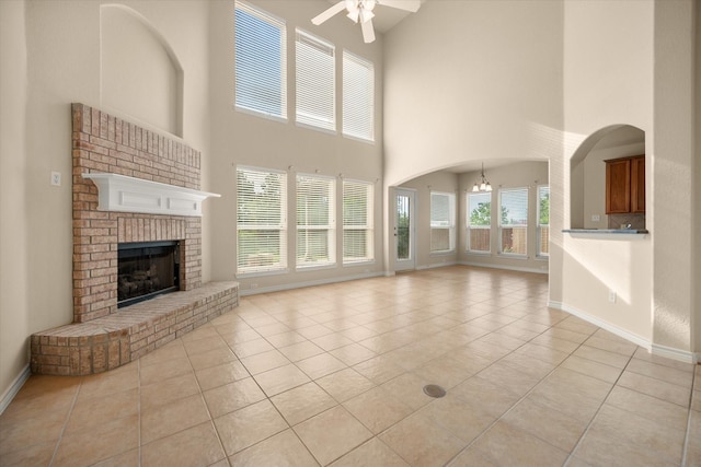 700 Sage Brush Dr, Weatherford, TX 76087 - unfurnished living room with ceiling fan, light tile patterned floors, a high ceiling, a fireplace, and baseboards