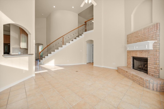 700 Sage Brush Dr, Weatherford, TX 76087 - unfurnished living room featuring a high ceiling, arched walkways, tile patterned flooring, a ceiling fan, and a brick fireplace