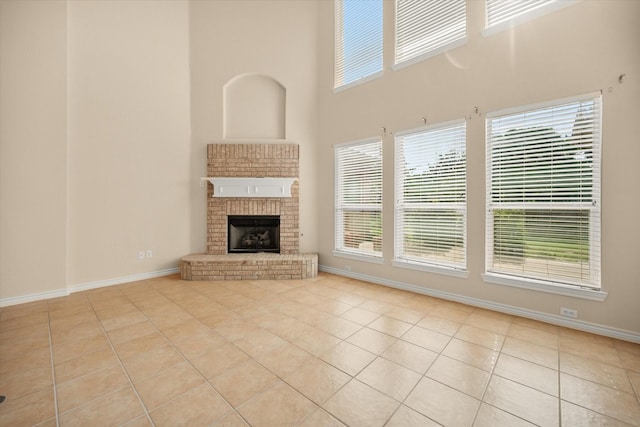 700 Sage Brush Dr, Weatherford, TX 76087 - unfurnished living room featuring tile patterned flooring, a towering ceiling, baseboards, and a brick fireplace
