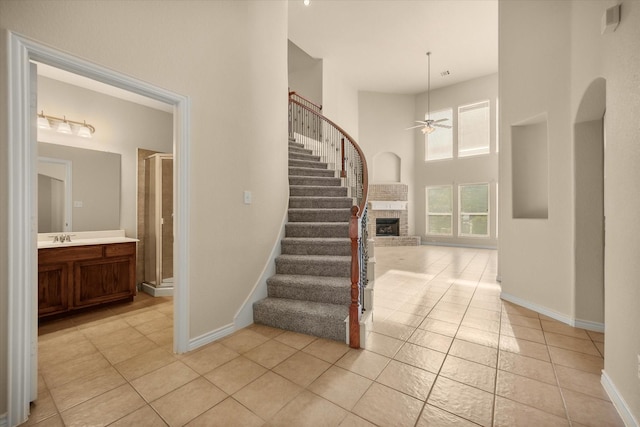 700 Sage Brush Dr, Weatherford, TX 76087 - stairway featuring a ceiling fan, tile patterned flooring, baseboards, a high ceiling, and a fireplace