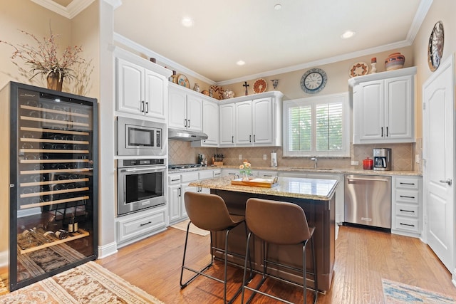 706 E 1st St, Fort Worth, TX 76102 - kitchen with appliances with stainless steel finishes, beverage cooler, under cabinet range hood, a breakfast bar area, and light stone countertops