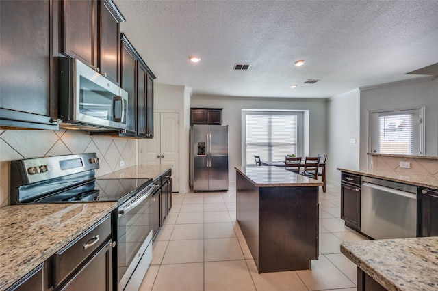 11812 Patton Dr, Frisco, TX 75036 - kitchen with appliances with stainless steel finishes, healthy amount of natural light, tasteful backsplash, a kitchen island, and a textured ceiling