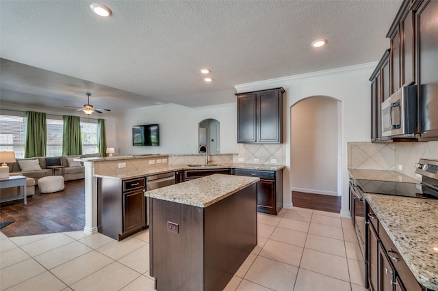 11812 Patton Dr, Frisco, TX 75036 - kitchen with stainless steel appliances, arched walkways, open floor plan, a peninsula, and recessed lighting