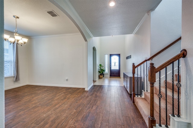 11812 Patton Dr, Frisco, TX 75036 - entryway featuring arched walkways, dark wood-style flooring, a chandelier, ornamental molding, and a textured ceiling