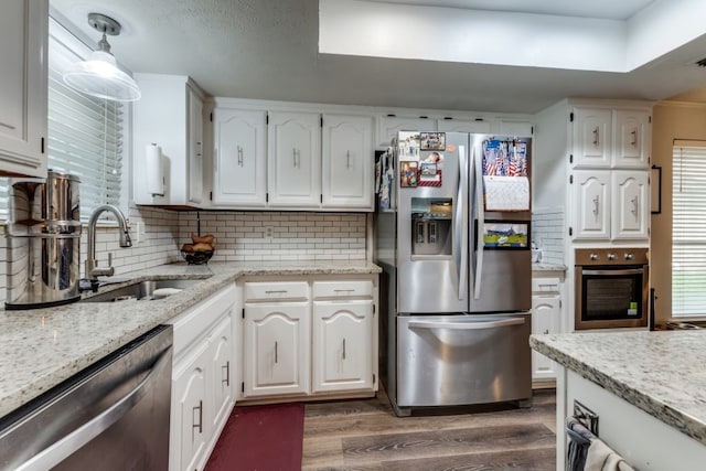 4937 Willowhaven Cir, Garland, TX 75043 - kitchen with stainless steel appliances, a sink, dark wood finished floors, white cabinetry, and backsplash