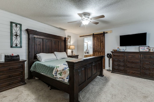 4937 Willowhaven Cir, Garland, TX 75043 - bedroom featuring a barn door, light colored carpet, a ceiling fan, wood walls, and a textured ceiling