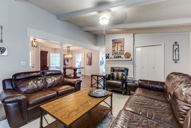 4937 Willowhaven Cir, Garland, TX 75043 - living room with beam ceiling, a brick fireplace, wood finished floors, ceiling fan, and a chandelier