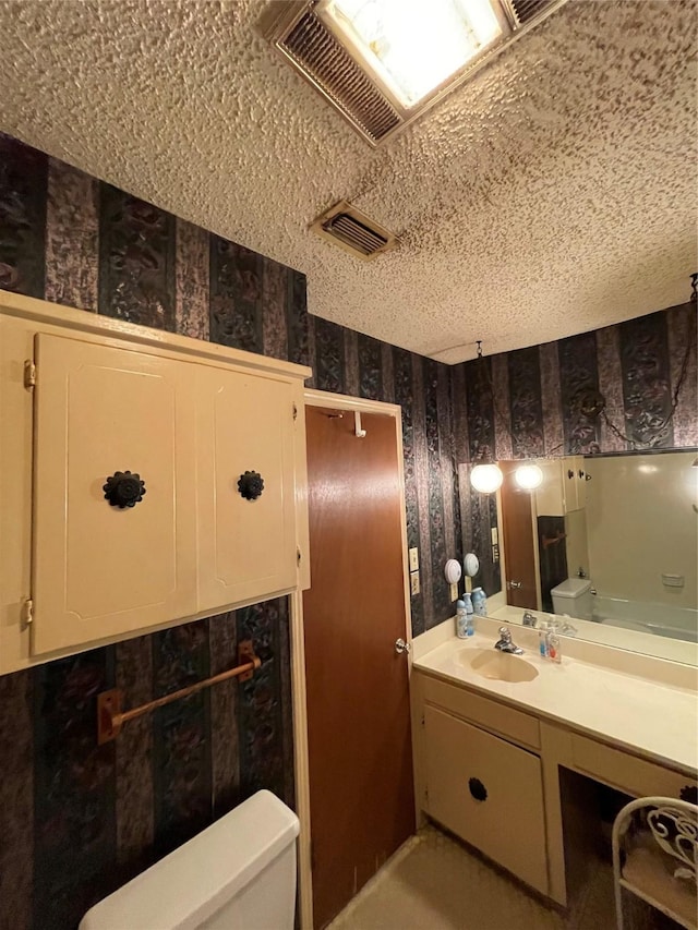 6320 Bocage Dr, Shreveport, LA 71119 - bathroom with wallpapered walls, toilet, vanity, and a textured ceiling