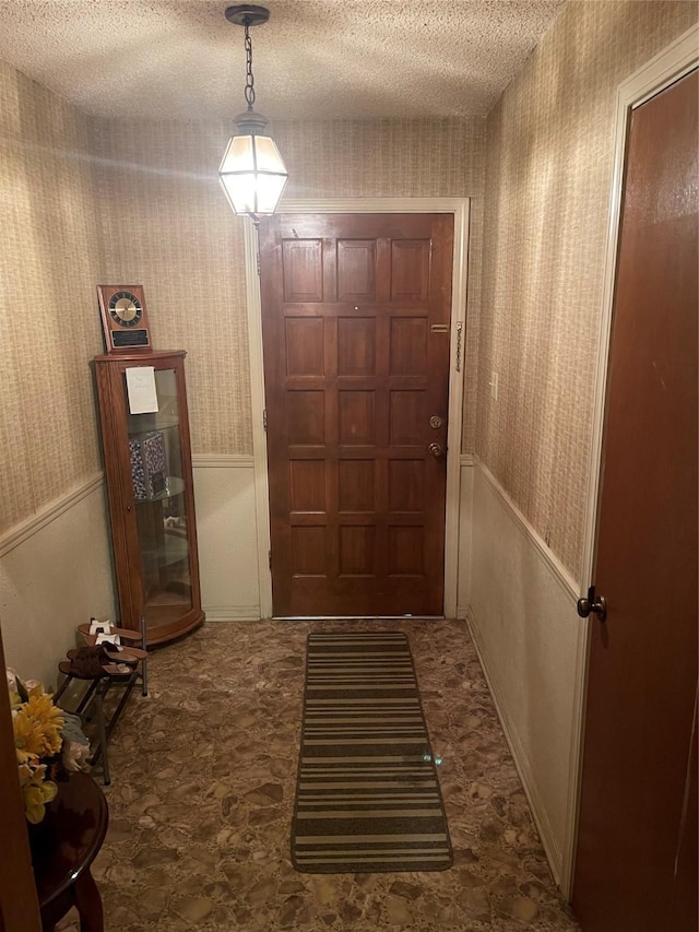 6320 Bocage Dr, Shreveport, LA 71119 - doorway to outside with wallpapered walls, a textured ceiling, and a wainscoted wall