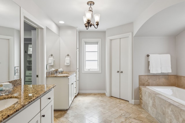 275 Casa Blanca Ave, Fort Worth, TX 76107 - full bathroom featuring two vanities, a garden tub, a chandelier, stone finish flooring, and baseboards