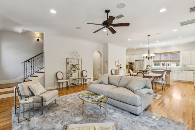 275 Casa Blanca Ave, Fort Worth, TX 76107 - living room featuring arched walkways, ceiling fan, light wood-type flooring, stairs, and a chandelier