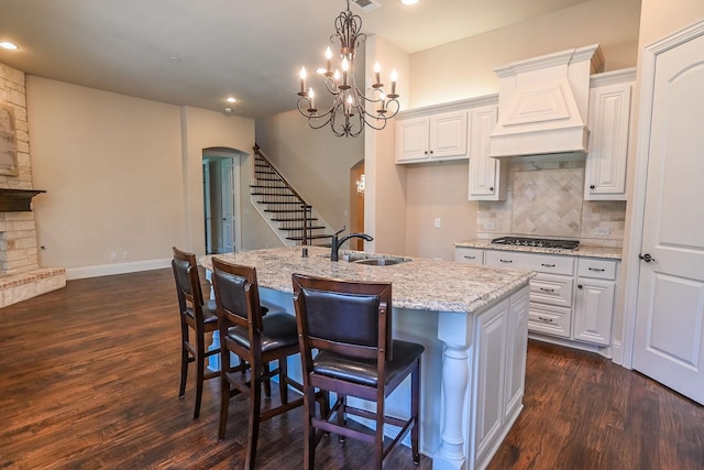 2230 Lewis Canyon Dr, Prosper, TX 75078 - kitchen with arched walkways, light stone countertops, dark wood-type flooring, a kitchen island with sink, and recessed lighting