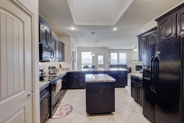 1300 Woodbine Cliff Dr, Fort Worth, TX 76179 - kitchen featuring black appliances, a peninsula, a kitchen island, light tile patterned floors, and recessed lighting