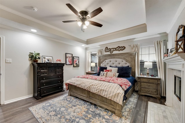 407 W Park Ave, Weatherford, TX 76086 - bedroom featuring a fireplace, wood finished floors, a raised ceiling, ceiling fan, and ornamental molding