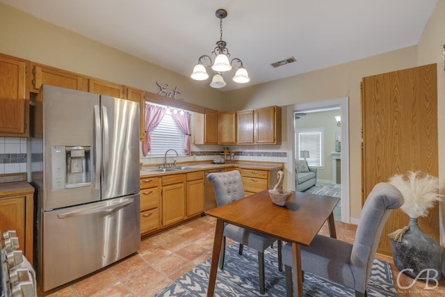 1126 Grand Ave, Abilene, TX 79605 - kitchen with appliances with stainless steel finishes, a sink, light countertops, a chandelier, and decorative backsplash