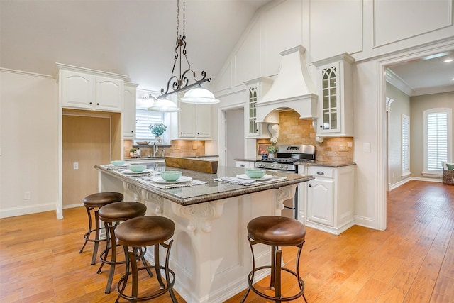 5800 Montford Dr, Colleyville, TX 76034 - kitchen featuring stainless steel gas range, custom range hood, a kitchen breakfast bar, a kitchen island, and crown molding
