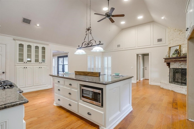 5800 Montford Dr, Colleyville, TX 76034 - kitchen featuring stainless steel microwave, ceiling fan, high vaulted ceiling, white cabinetry, and a kitchen island