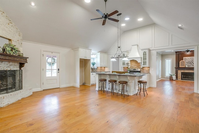 5800 Montford Dr, Colleyville, TX 76034 - kitchen with a brick fireplace, a ceiling fan, a kitchen bar, white cabinets, and high vaulted ceiling