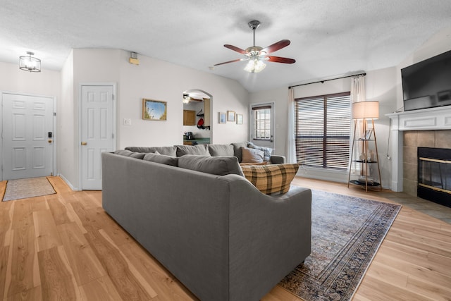 7612 Brittany Pl, Fort Worth, TX 76137 - living area with ceiling fan, a textured ceiling, a tiled fireplace, light wood-type flooring, and baseboards