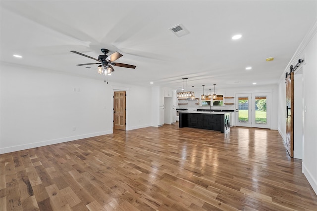 2925 Edmond Ave, Waco, TX 76707 - unfurnished living room featuring a barn door, recessed lighting, wood finished floors, baseboards, and ornamental molding