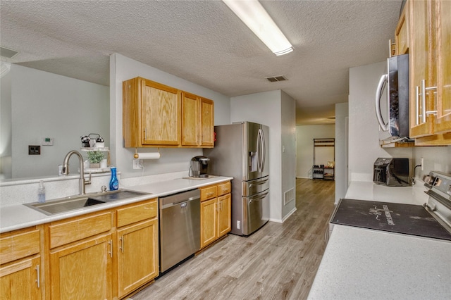 1209 Starpoint Ln, Wylie, TX 75098 - kitchen with appliances with stainless steel finishes, a sink, light wood-style floors, a textured ceiling, and light countertops