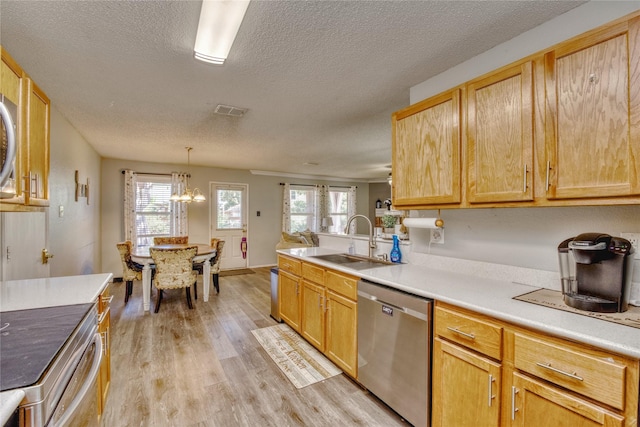 1209 Starpoint Ln, Wylie, TX 75098 - kitchen featuring appliances with stainless steel finishes, a sink, light wood-style flooring, a textured ceiling, and a chandelier