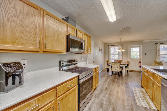 1209 Starpoint Ln, Wylie, TX 75098 - kitchen with stainless steel appliances, a textured ceiling, light wood finished floors, a chandelier, and light countertops