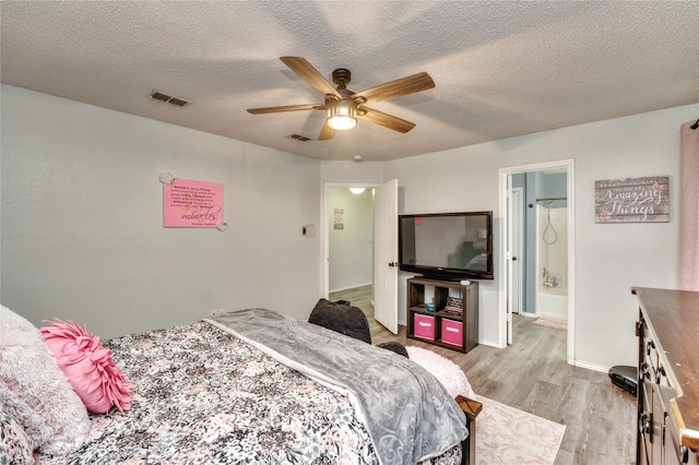 1209 Starpoint Ln, Wylie, TX 75098 - bedroom featuring light wood-style floors, a textured ceiling, baseboards, a ceiling fan, and ensuite bath