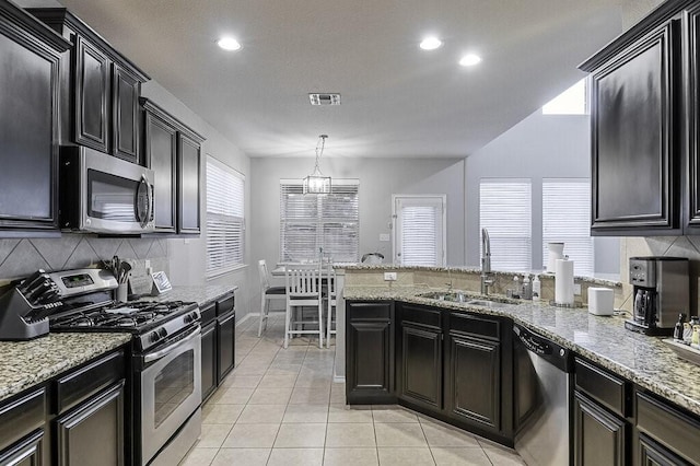 925 Lake Grove Dr, Little Elm, TX 75068 - kitchen with stainless steel appliances, a sink, backsplash, a peninsula, and light stone countertops