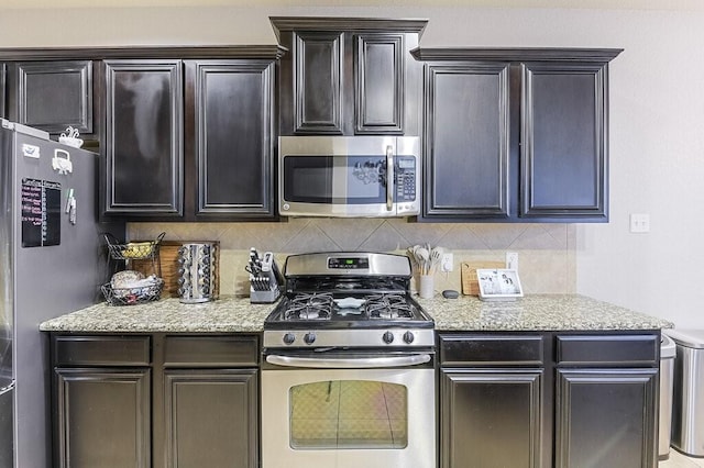 925 Lake Grove Dr, Little Elm, TX 75068 - kitchen with appliances with stainless steel finishes, decorative backsplash, light stone countertops, and dark brown cabinets