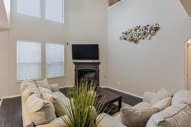 925 Lake Grove Dr, Little Elm, TX 75068 - living area featuring dark wood-style flooring, baseboards, a fireplace, healthy amount of natural light, and a towering ceiling