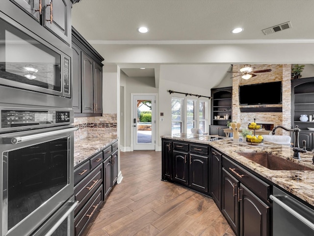 501 Las Lomas Dr, Heath, TX 75032 - kitchen featuring stainless steel appliances, open floor plan, light stone countertops, light wood-type flooring, and tasteful backsplash