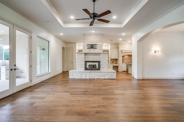 6005 Selkirk Ct, Cleburne, TX 76033 - unfurnished living room featuring a raised ceiling, ceiling fan, light wood-style floors, crown molding, and a fireplace