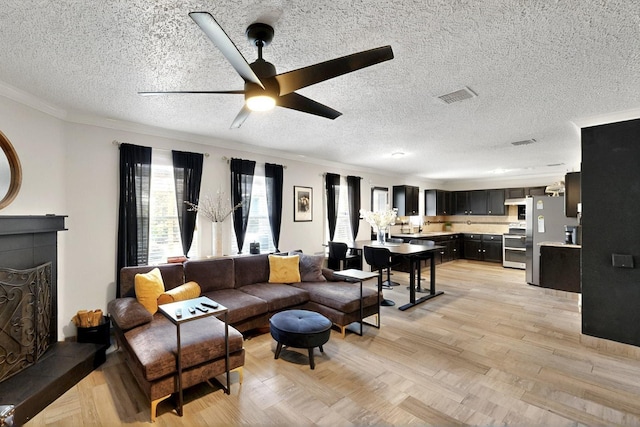 2908 Quail Run Dr, Mesquite, TX 75149 - living room with ceiling fan, crown molding, a textured ceiling, a tiled fireplace, and parquet flooring