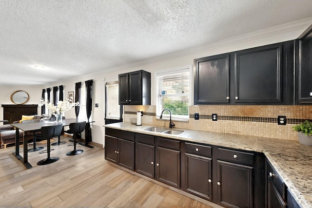 2908 Quail Run Dr, Mesquite, TX 75149 - kitchen featuring a sink, light wood finished floors, decorative backsplash, crown molding, and a textured ceiling