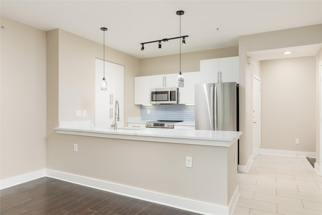 4605 Cedar Springs Rd Unit 201, Dallas, TX 75219 - kitchen featuring stainless steel appliances, backsplash, a peninsula, a sink, and pendant lighting