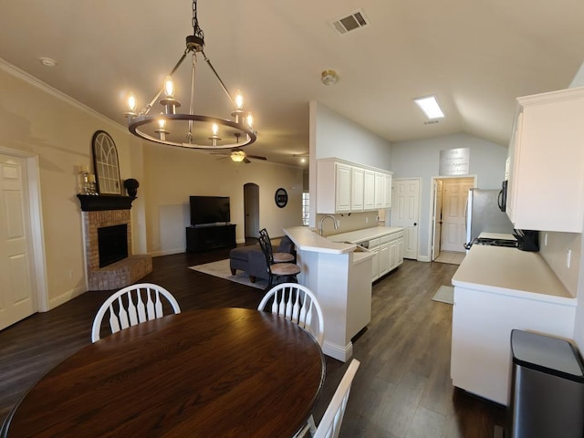 4415 Shady Elm Dr, Mansfield, TX 76063 - dining room featuring ceiling fan, vaulted ceiling, a chandelier, dark wood-type flooring, and a brick fireplace