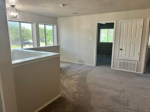 8412 Widgeon Way, Dallas, TX 75249 - spare room with a textured ceiling, carpet flooring, and a chandelier