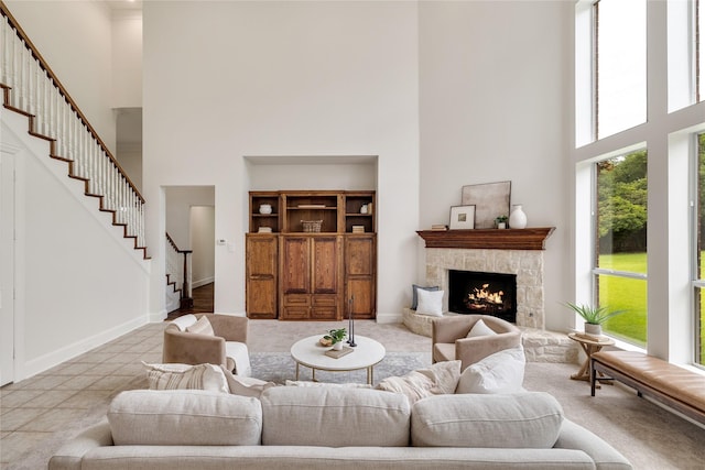 6408 Riverside Dr, Plano, TX 75024 - living room featuring a towering ceiling, stairs, a stone fireplace, baseboards, and carpet flooring