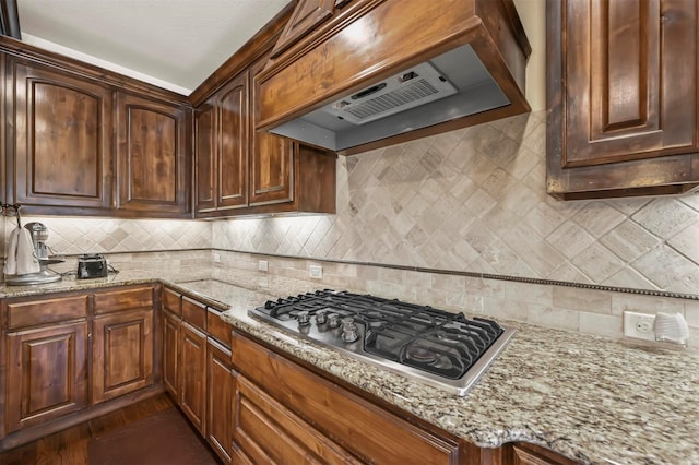 13818 Mammoth Cave Ln, Frisco, TX 75035 - kitchen featuring stainless steel gas cooktop, premium range hood, tasteful backsplash, and light stone countertops
