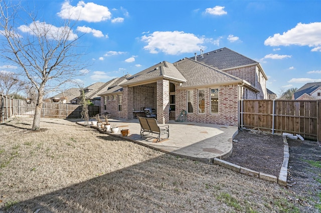 13818 Mammoth Cave Ln, Frisco, TX 75035 - rear view of house featuring brick siding, a shingled roof, a fenced backyard, and a patio area