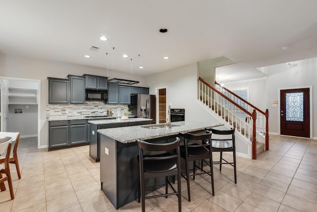 851 Carolina Way, Lantana, TX 76226 - kitchen with a kitchen island with sink, appliances with stainless steel finishes, light tile patterned flooring, a sink, and decorative backsplash